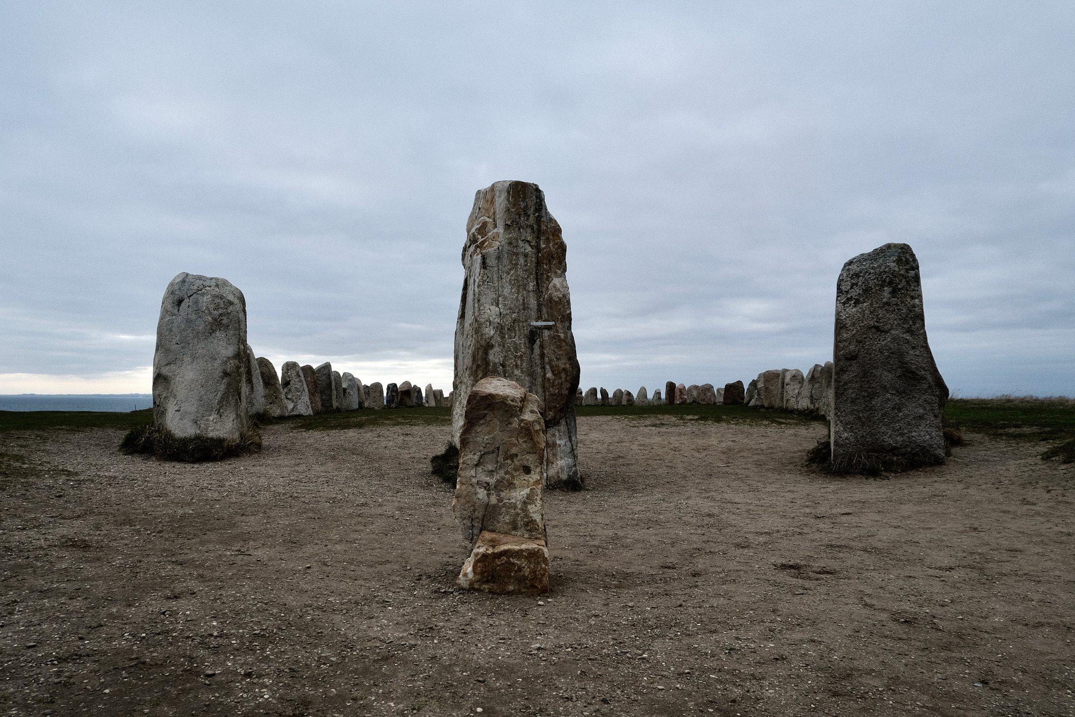 Ales Stenar stone ship in Kåseberga, Sweden, with large standing stones arranged in a ship formation under a grey cloudy sky.