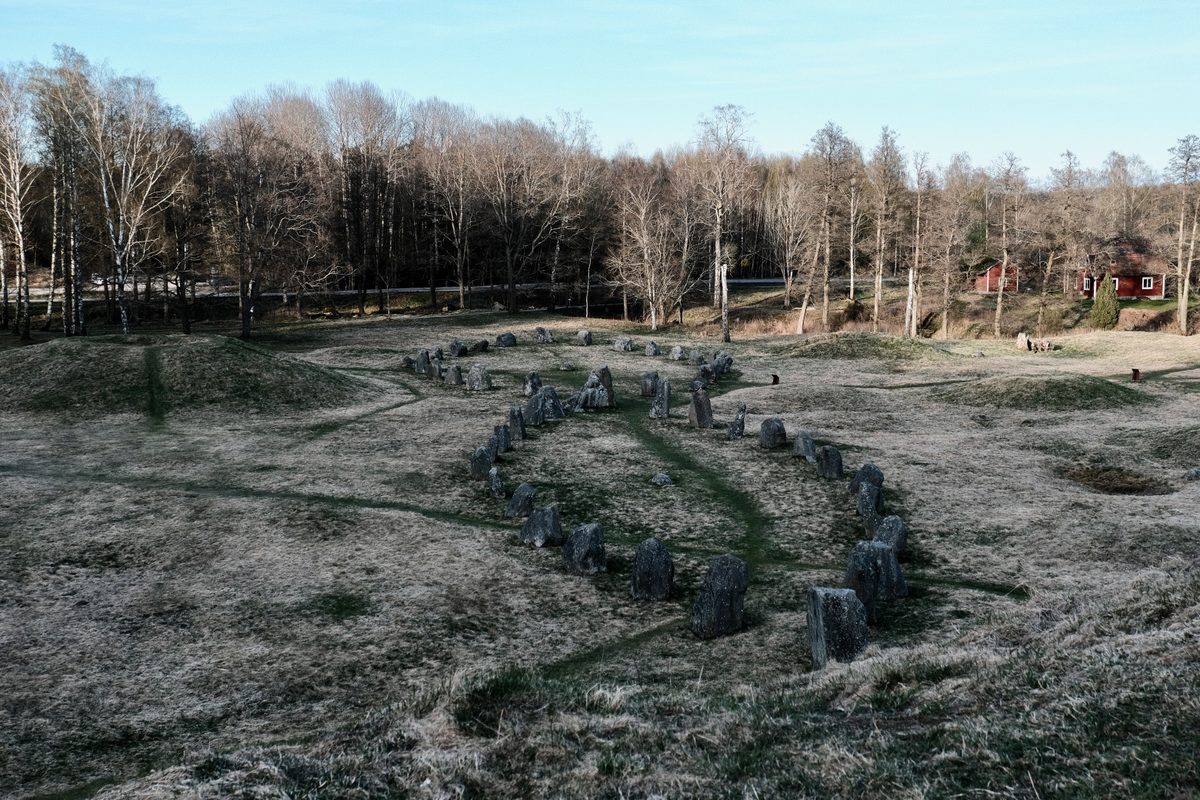 A stone ship formation at Anundshög in Västerås, Sweden, surrounded by grassy burial mounds, leafless trees, and open Nordic landscape.